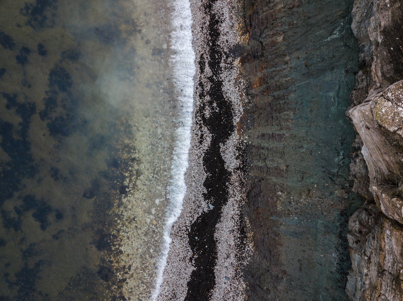 about-03 A stunning aerial view of a rocky shoreline with crashing waves and diverse textures.
