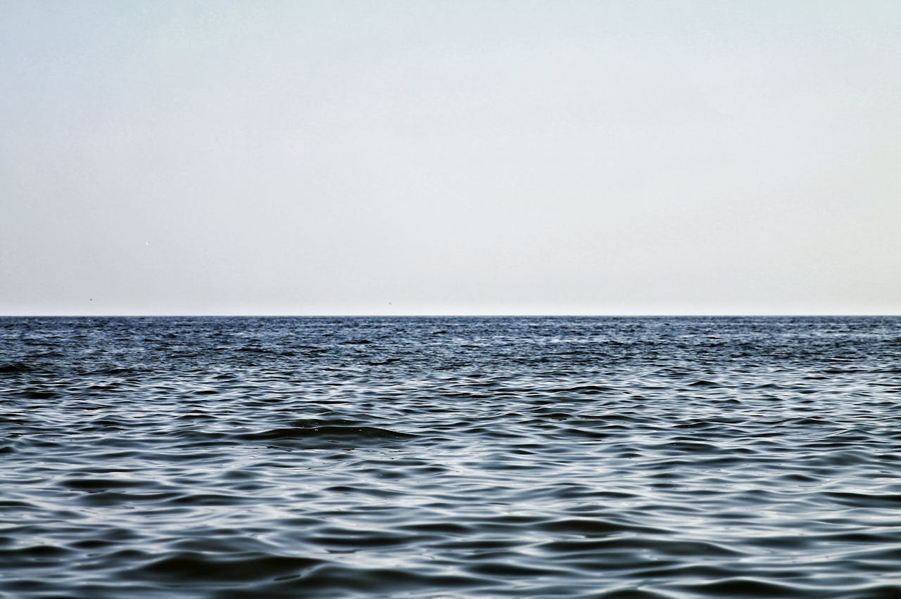 about-02 Serene view of an endless ocean horizon beneath a clear blue sky, capturing tranquility and natures beauty.